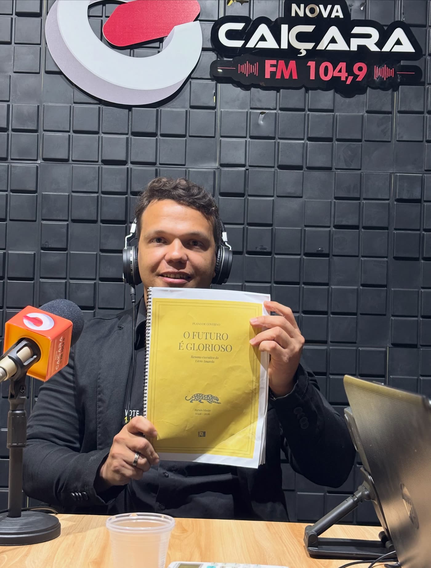 Vinícius Chagas em entrevista de rádio, segurando o Livro Amarelo